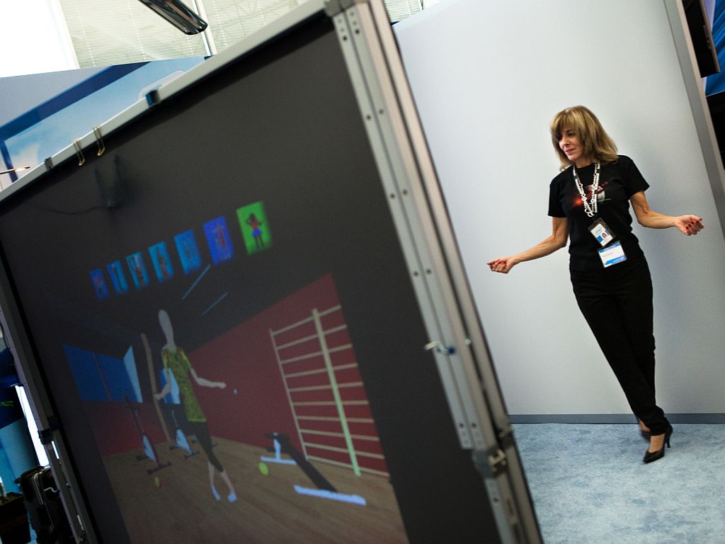 A researcher stands in front of a large screen that overlays a garment onto her body in real time.