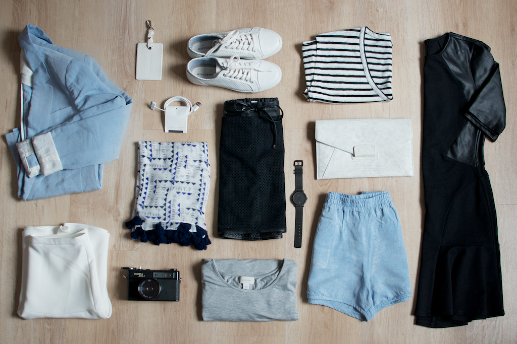 A small travel capsule wardrobe laid out flat: a few tops, bottoms and shoes that combine.